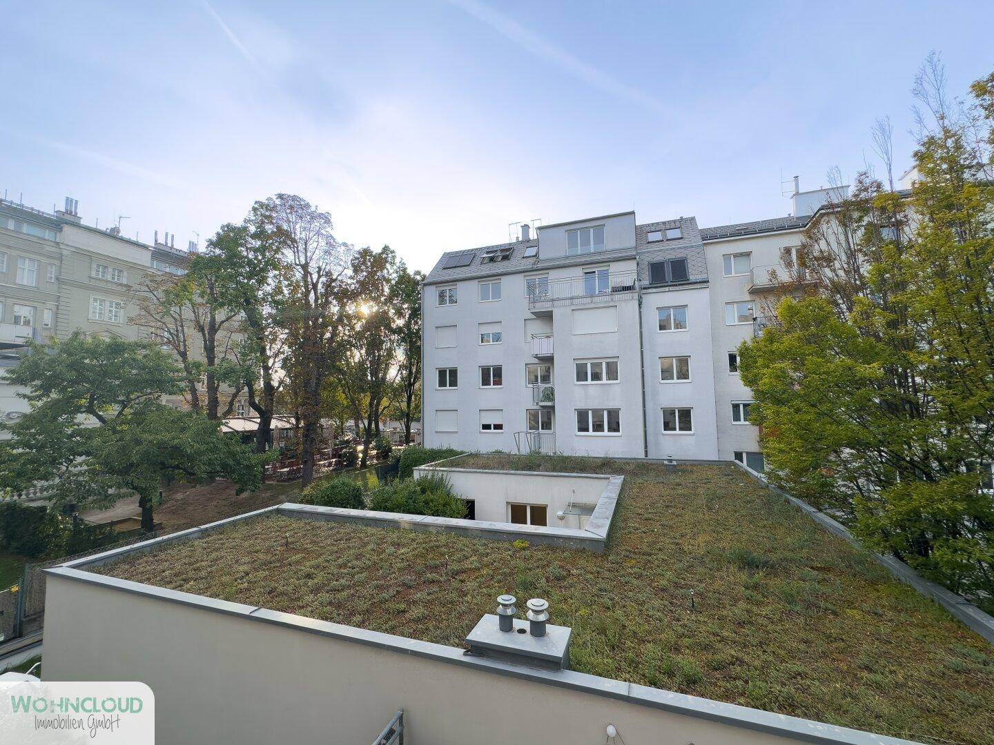 Balkon mit weitem Blick über die Stadt und die grünen Dächer der Nachbargebäude.