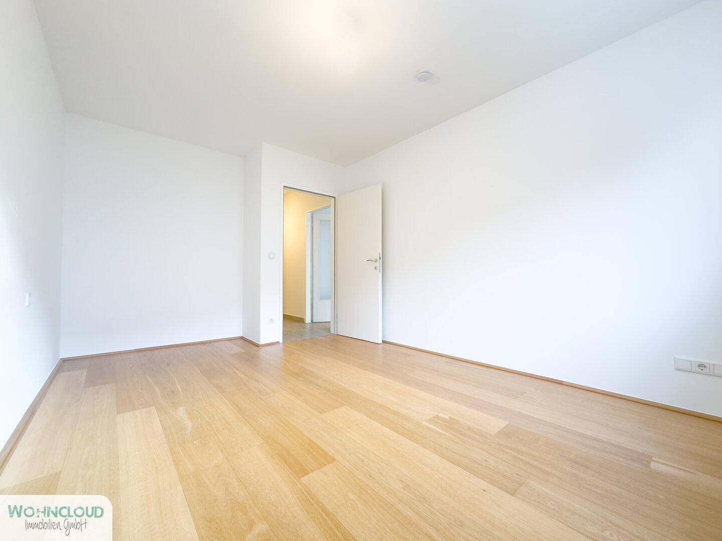Leeres Schlafzimmer mit hellem Holzboden und weiß gestrichenen Wänden, bereit zur Einrichtung.