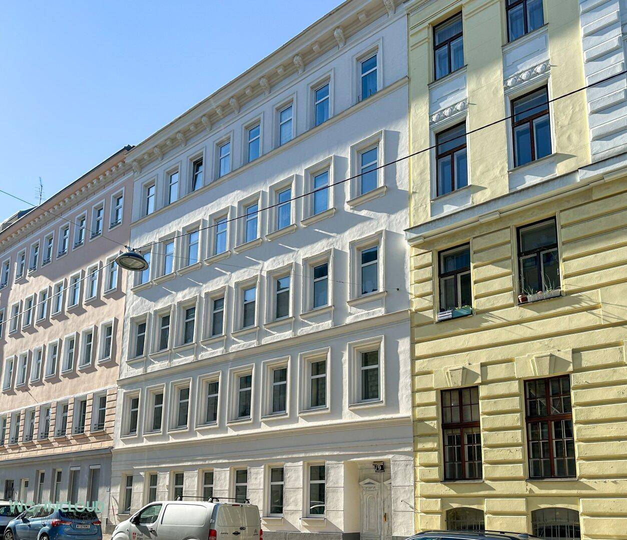 Historische Gebäudefassade mit vielen Fenstern an einem sonnigen Tag.