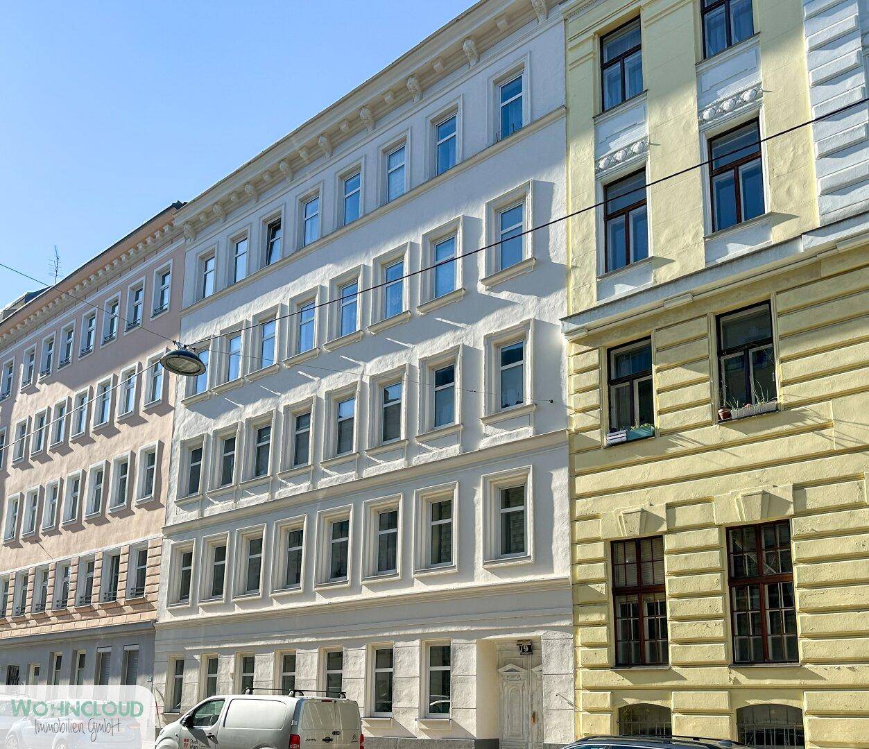 Historische Fassade eines Mehrfamilienhauses in der Stadt mit vielen Fenstern und Details.