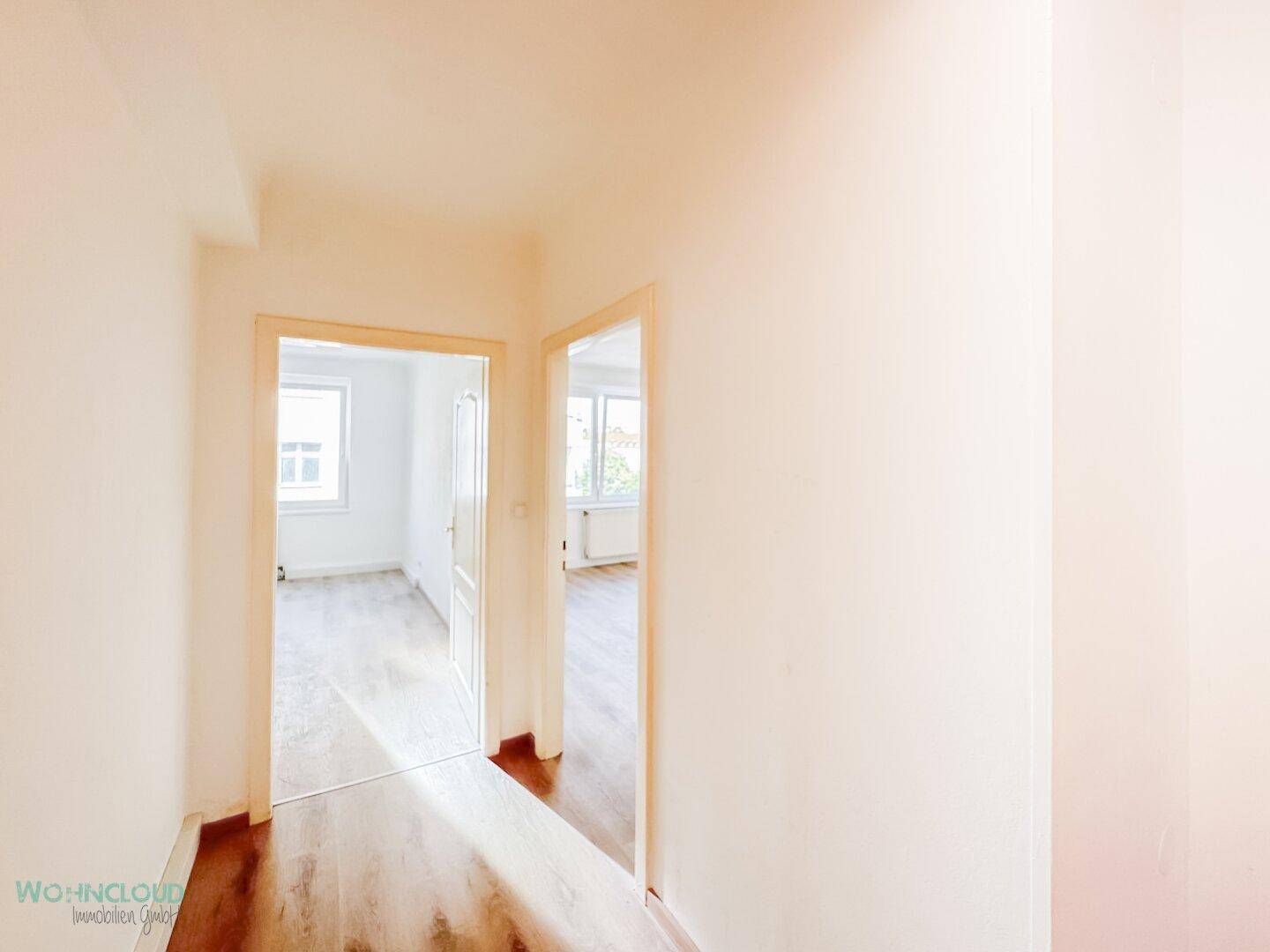 Heller Flur mit Holzboden, der zu weiteren Zimmern der Wohnung führt.