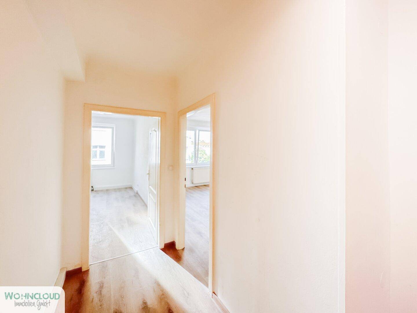 Heller Flur mit Laminatboden, der zu verschiedenen Zimmern der Wohnung führt.