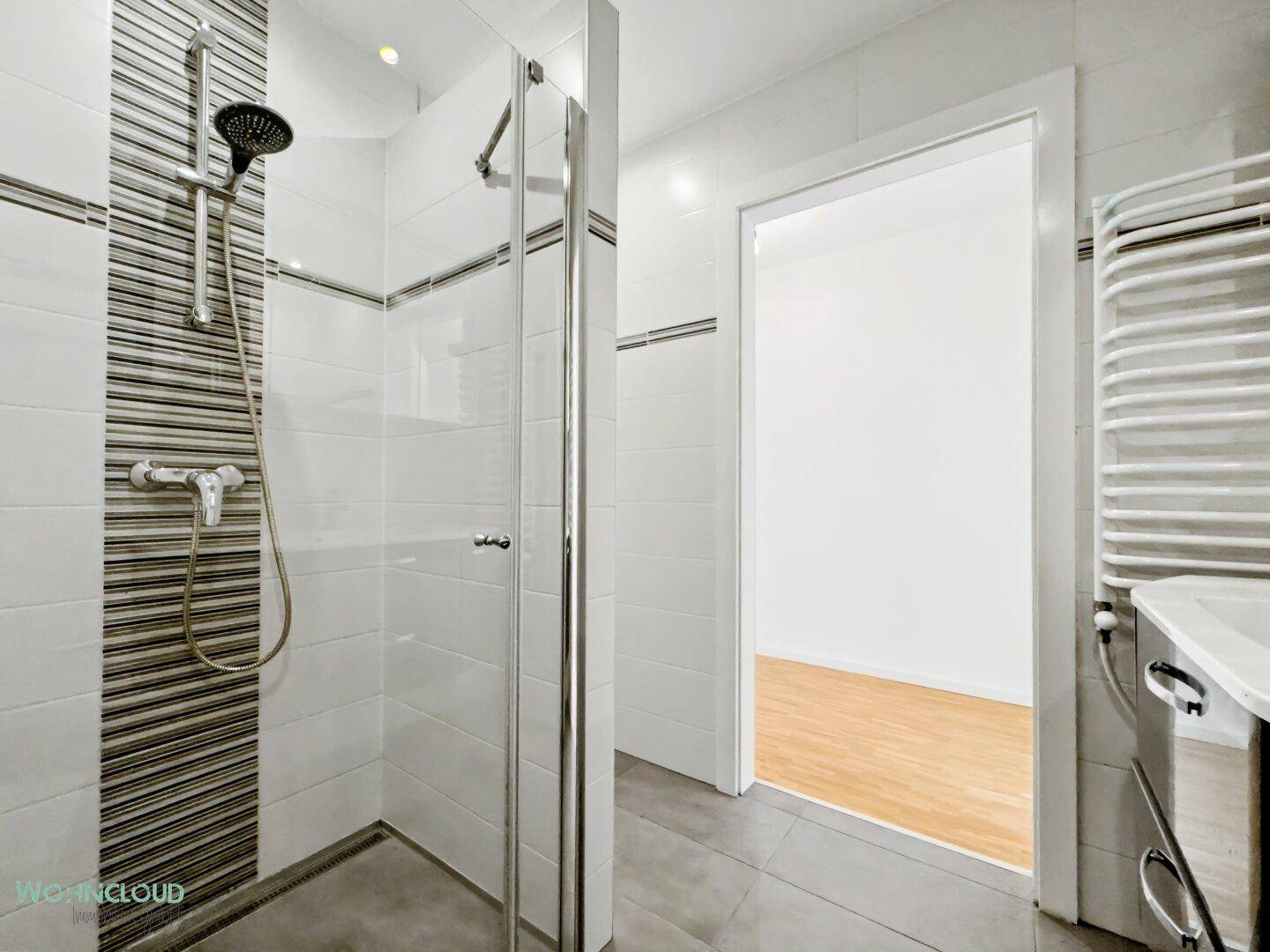 Modernes Badezimmer mit ebenerdiger Dusche, Fliesen und Handtuchheizkörper.