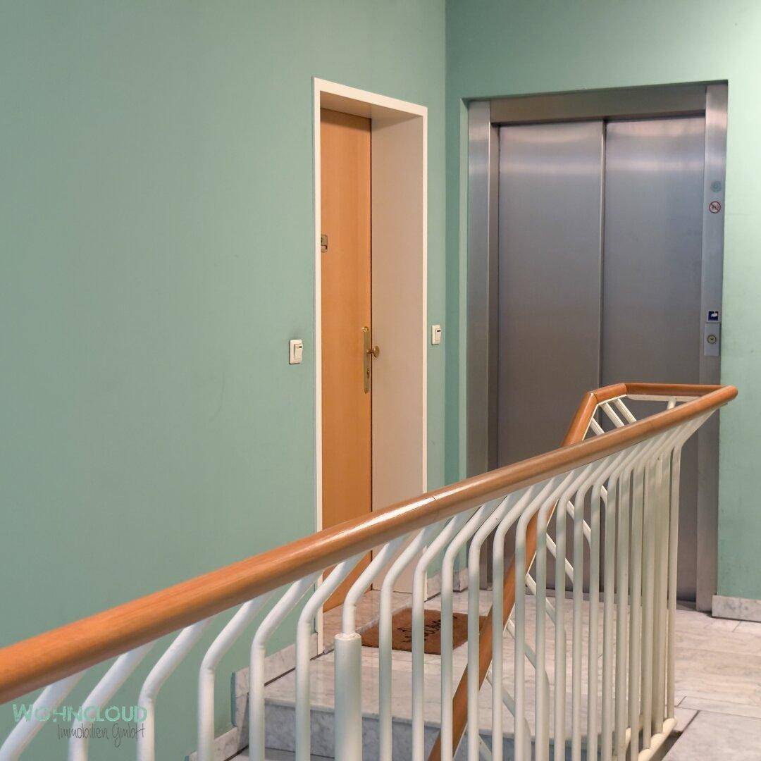Treppenhaus mit Marmorstufen, Geländer und einem Aufzug für bequemen Zugang zu den Etagen.