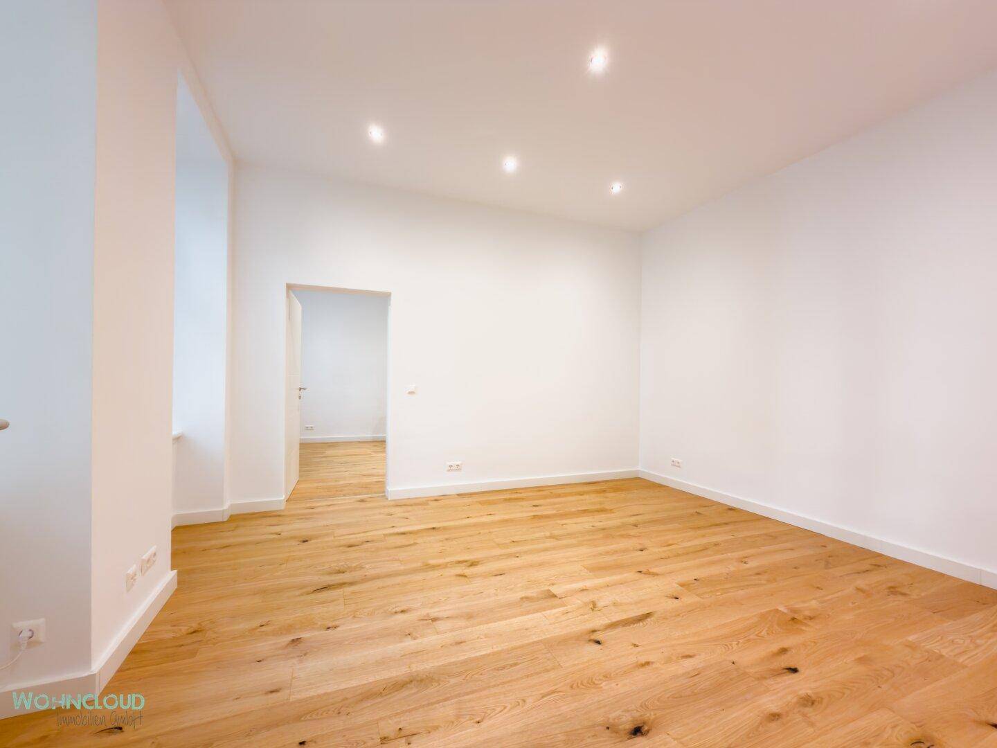 Geräumiges, helles Zimmer mit Holzboden und weißen Wänden, bereit zur Einrichtung.