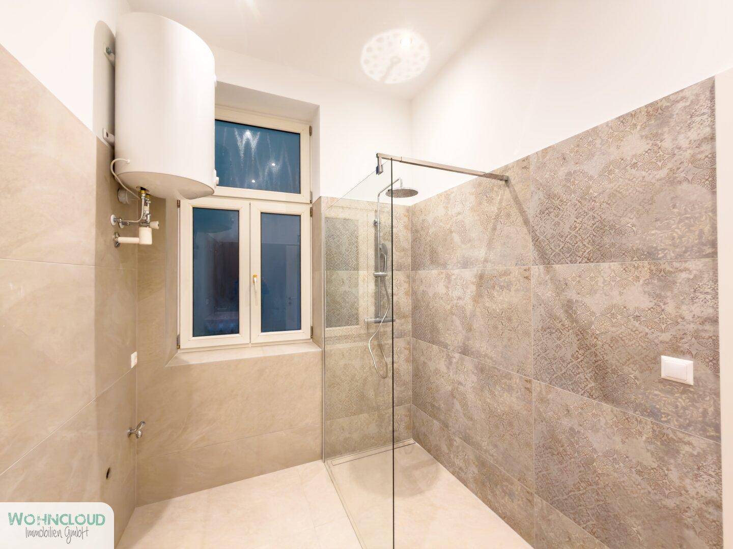 Helles Badezimmer mit großer begehbarer Dusche und Fenster für natürliche Belüftung.