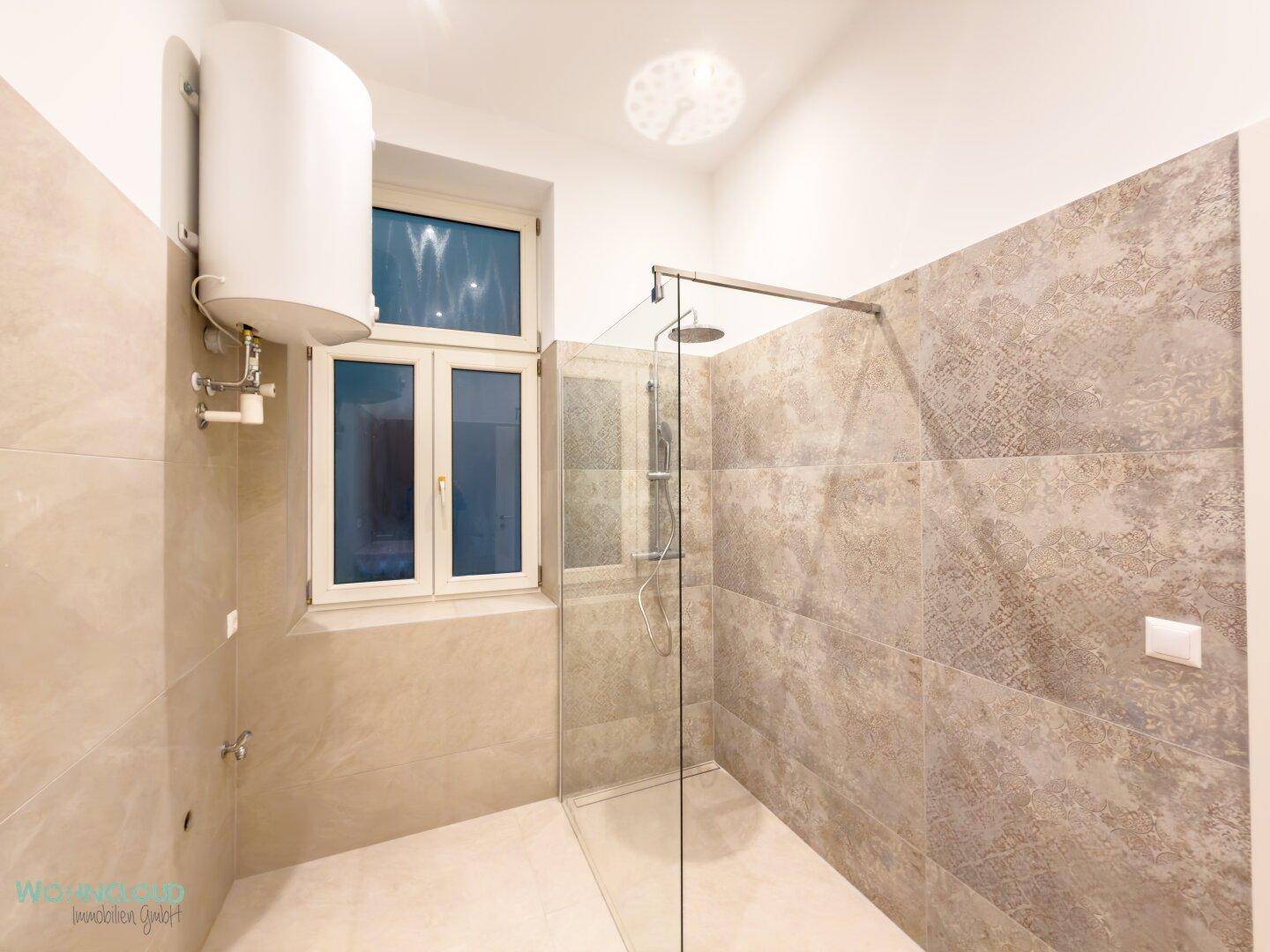 Helles Badezimmer mit Fenster, begehbarer Dusche und beigefarbenen Wand- und Bodenfliesen für ein modernes Ambiente.