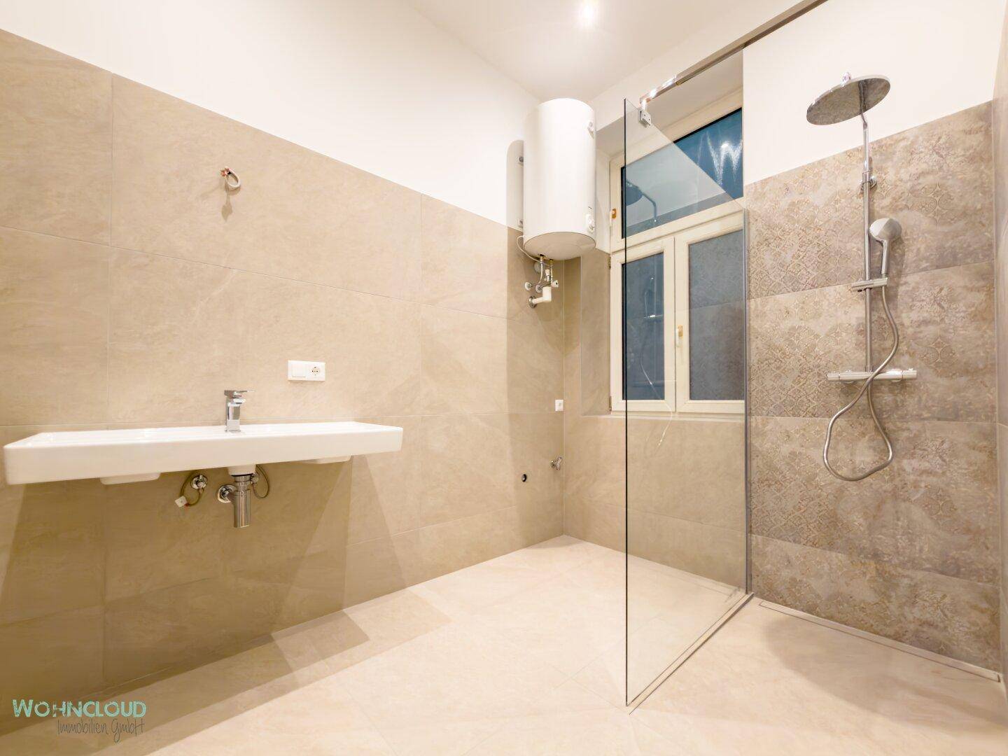 Modernes Badezimmer mit begehbarer Dusche, großformatigen Fliesen und einem eleganten Waschbecken.