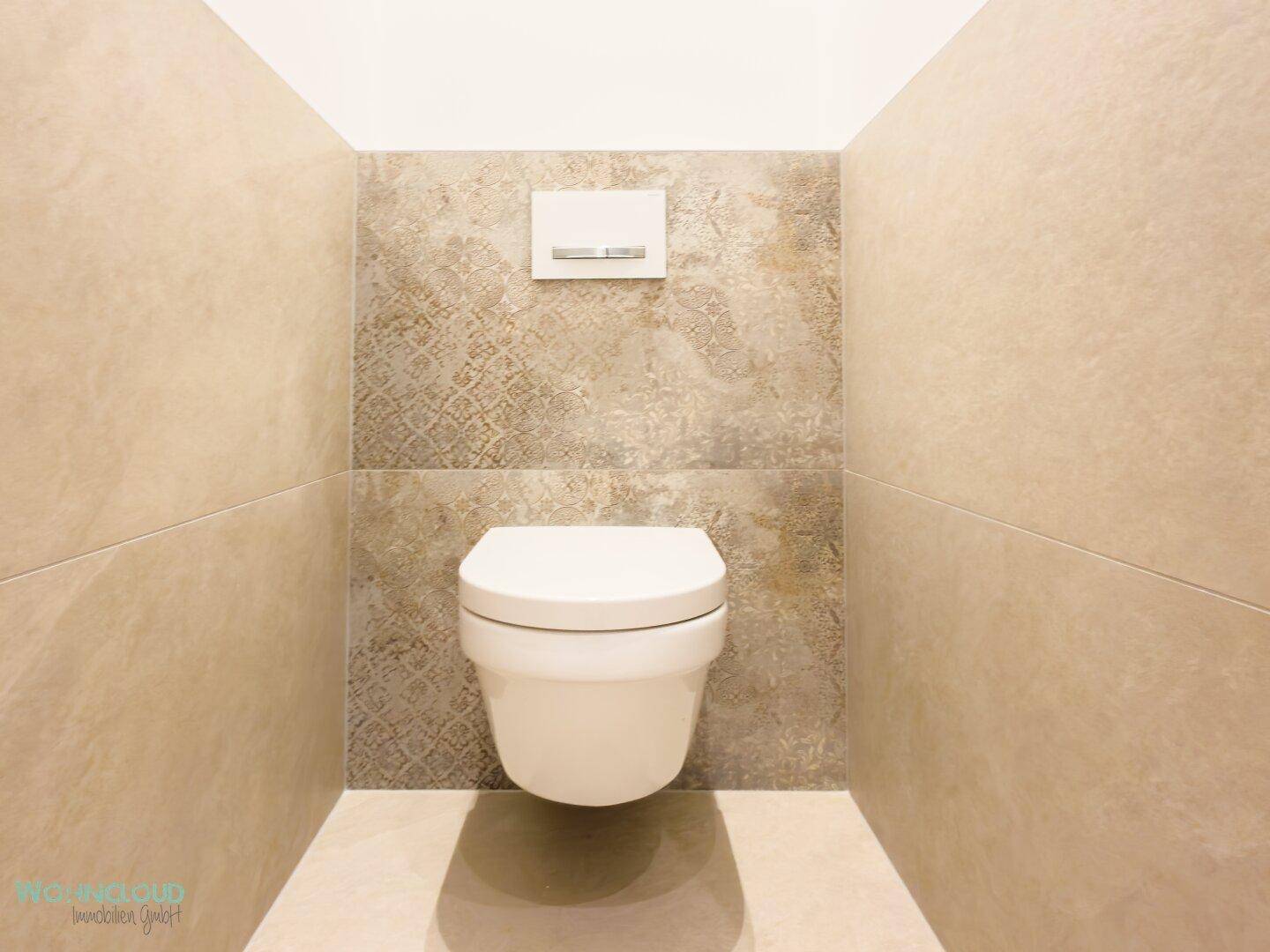 Separates WC mit wandhängender Toilette und modernen Fliesen in neutralen Farbtönen, sehr gepflegt.