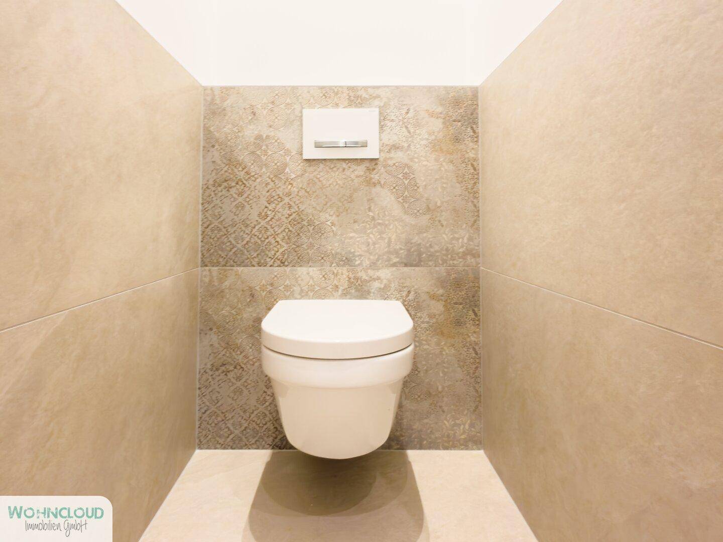 Separates WC mit wandhängender Toilette und modernen Fliesen an den Wänden.