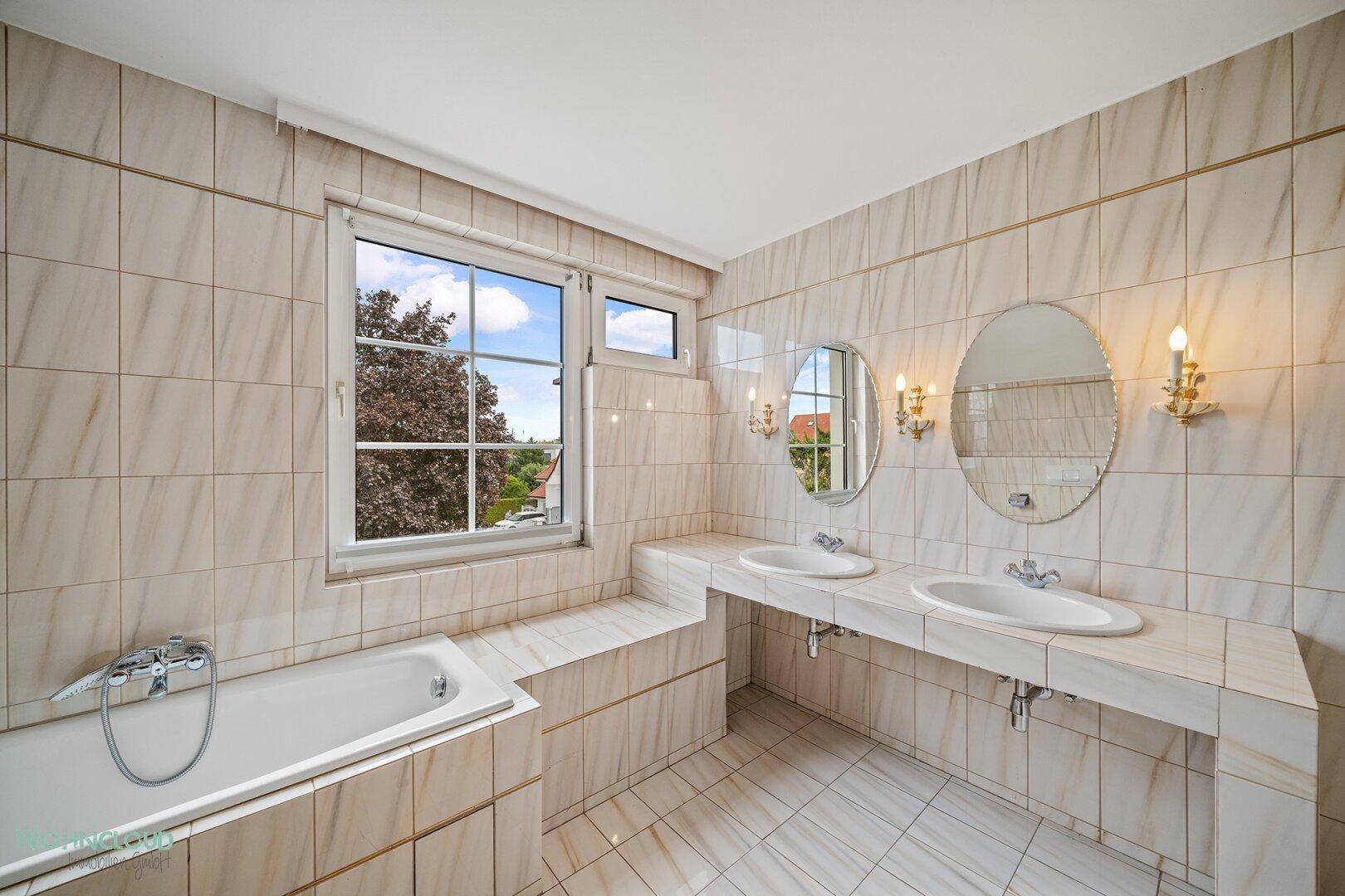 Geräumiges Badezimmer mit beigefarbenen Fliesen, Doppelwaschbecken und Badewanne.