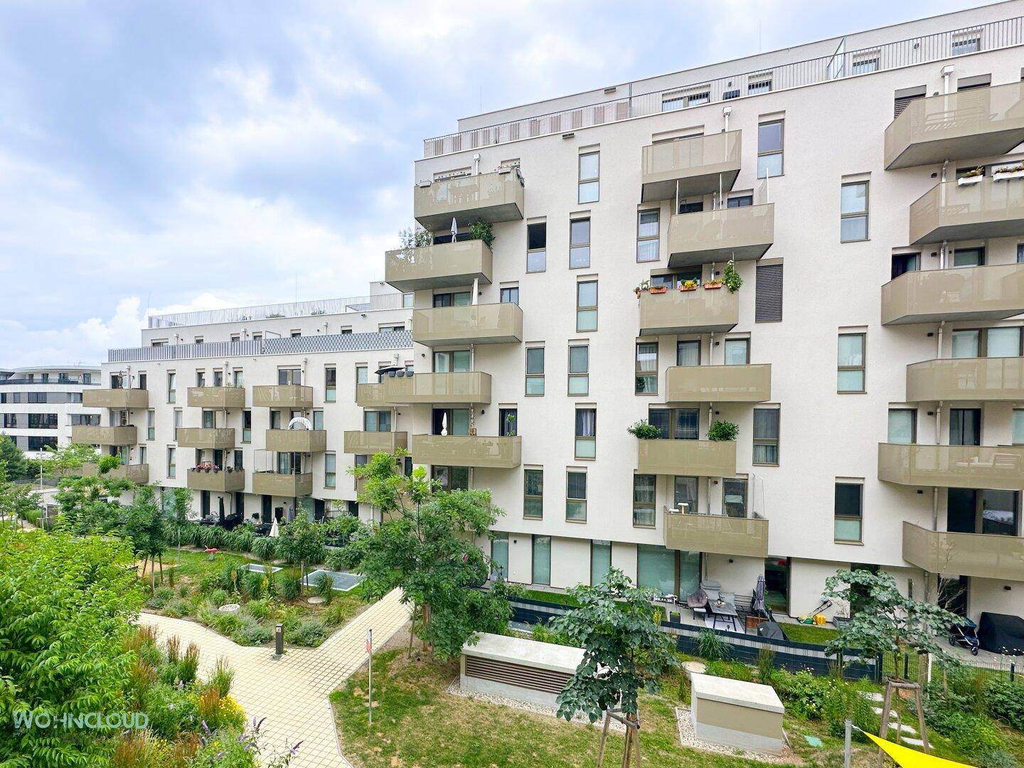 Ansicht eines modernen Wohnkomplexes mit vielen Balkonen und begrünten Außenbereichen.
