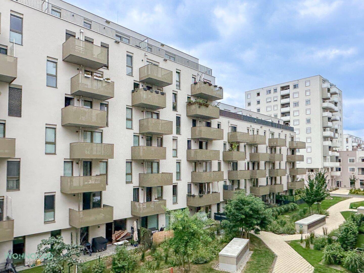Weitläufiger Blick auf die moderne Wohnanlage mit mehreren Gebäuden und Grünflächen.