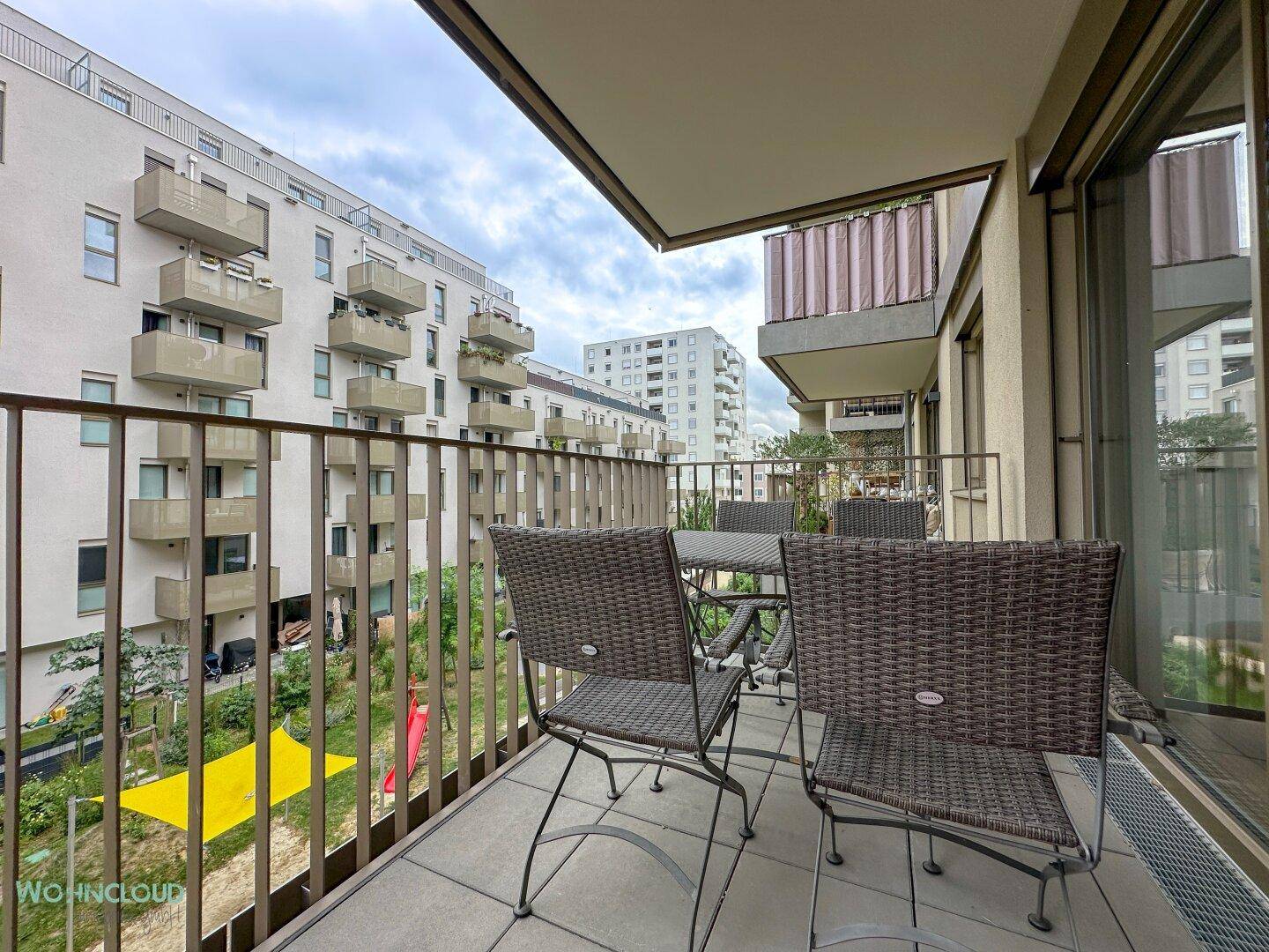 Gemütlicher Balkon mit Sitzgelegenheiten und Blick auf die umliegende Wohnanlage.