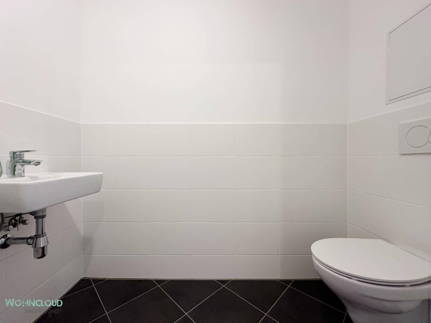 Separates Gäste-WC mit wandhängendem WC und kleinem Handwaschbecken.