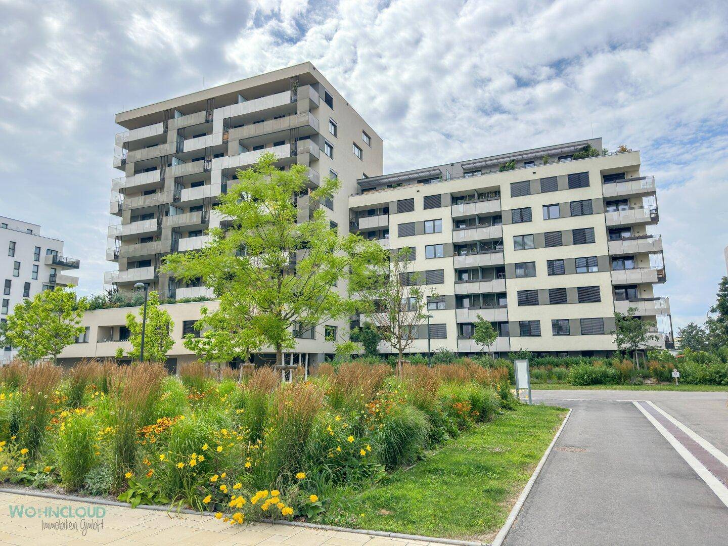 Weitläufige Ansicht des modernen Wohnkomplexes mit gepflegten Grünflächen und Bäumen.