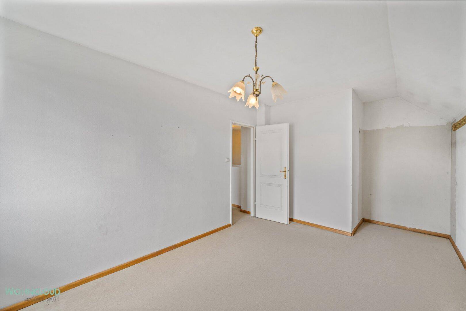 Helles Schlafzimmer mit Teppichboden und schrägen Wänden im Dachgeschoss.
