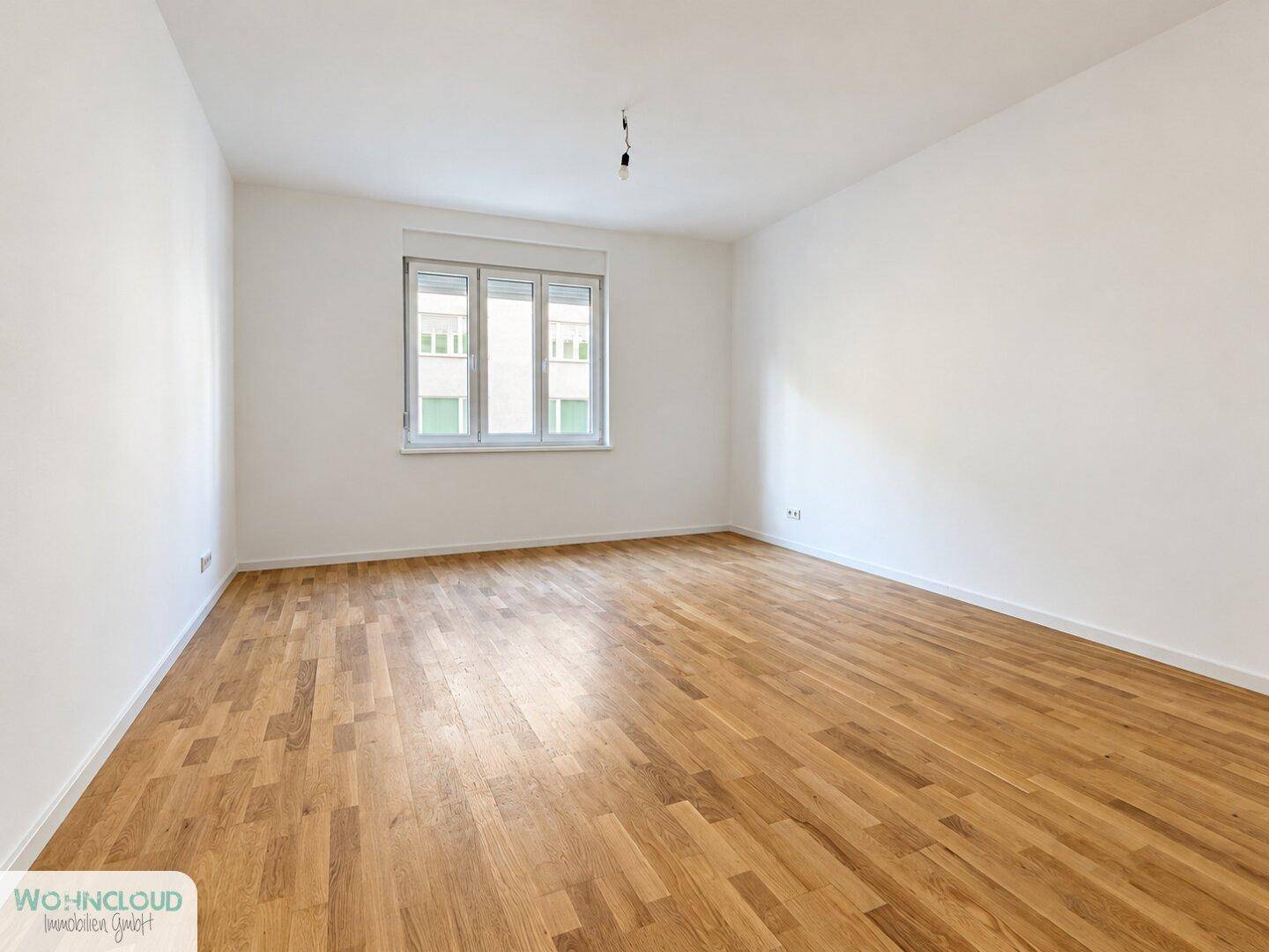 Heller, leerer Raum mit weißen Wänden und klassischem Holzparkettboden, ideal für individuelle Gestaltung.
