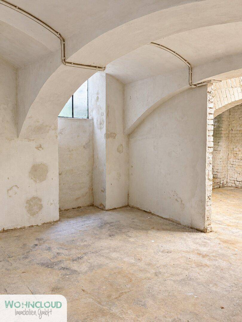Kellerraum mit gewölbten Decken, unverputzten Wänden und einem kleinen Fenster.