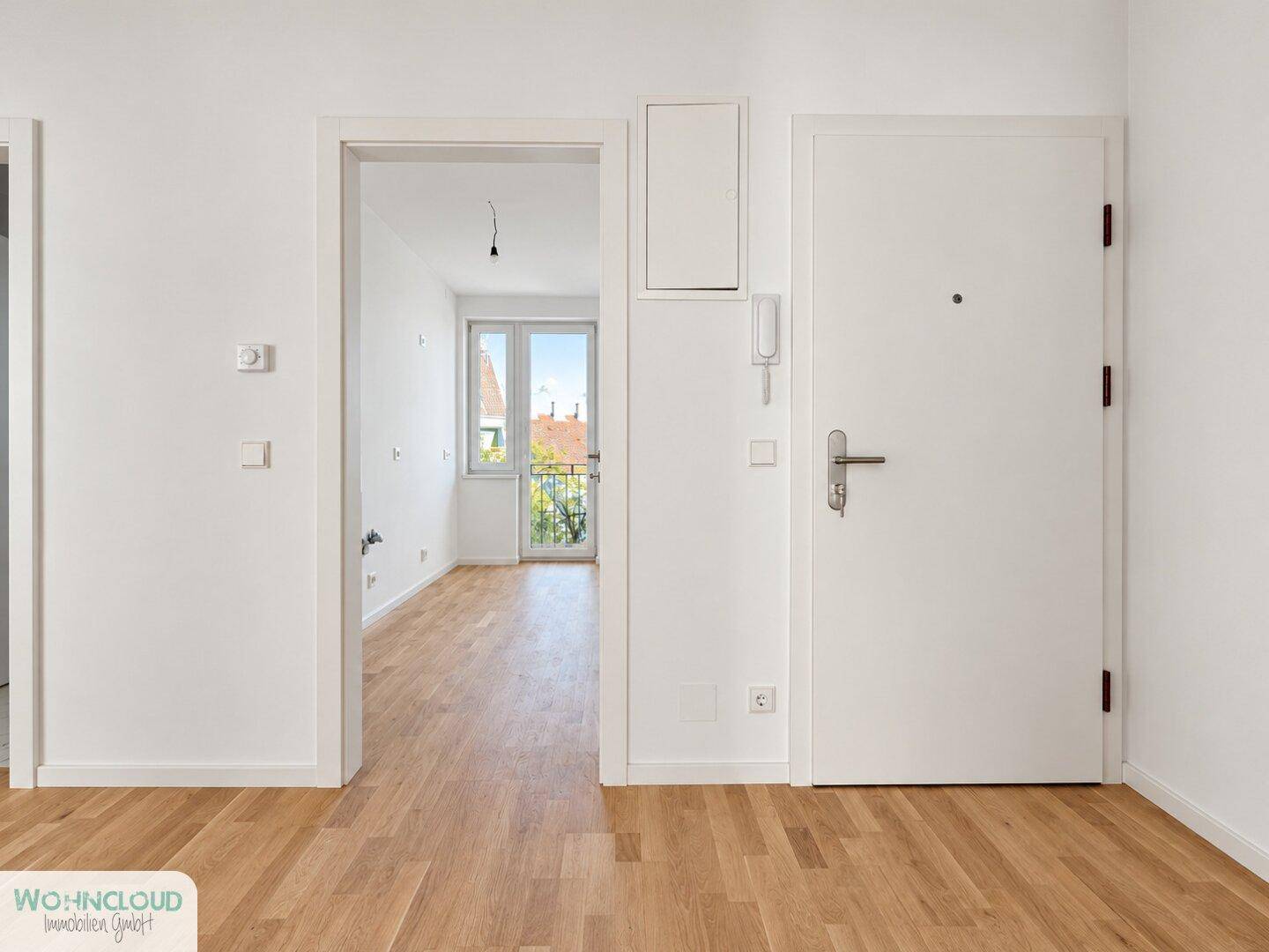Heller Eingangsbereich mit Holzboden und Zugang zu weiteren Zimmern mit französischem Balkon.