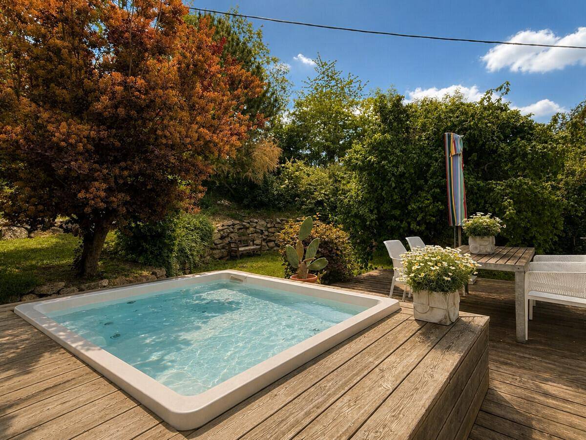 Entspannungsbereich mit Whirlpool auf einer Holzterrasse, umgeben von üppigem Grün.