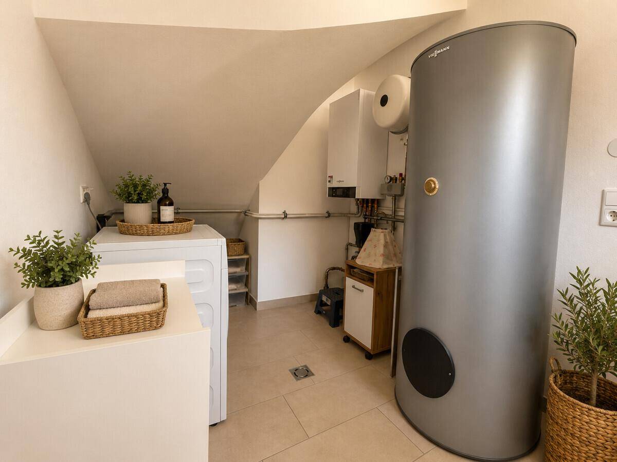 Praktischer Hauswirtschaftsraum mit Heizungsanlage, Waschmaschine und Dachschräge.