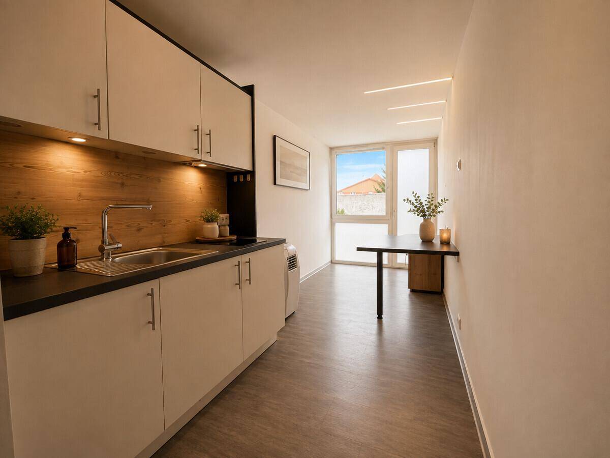 Helle Küchenzeile mit Holzrückwand und Essbereich, der zu einem großen Fenster führt.