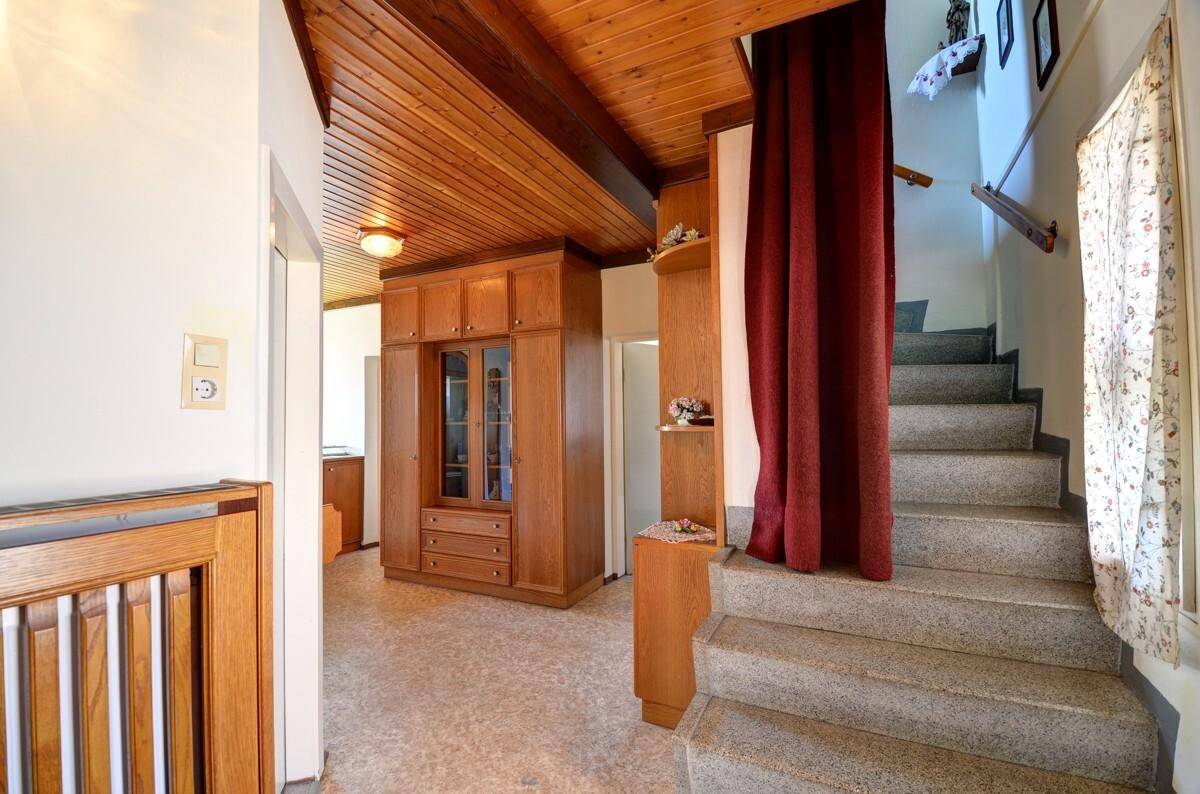 Eingangsbereich mit Holzdecke, Einbauschrank und Treppe zum Obergeschoss.