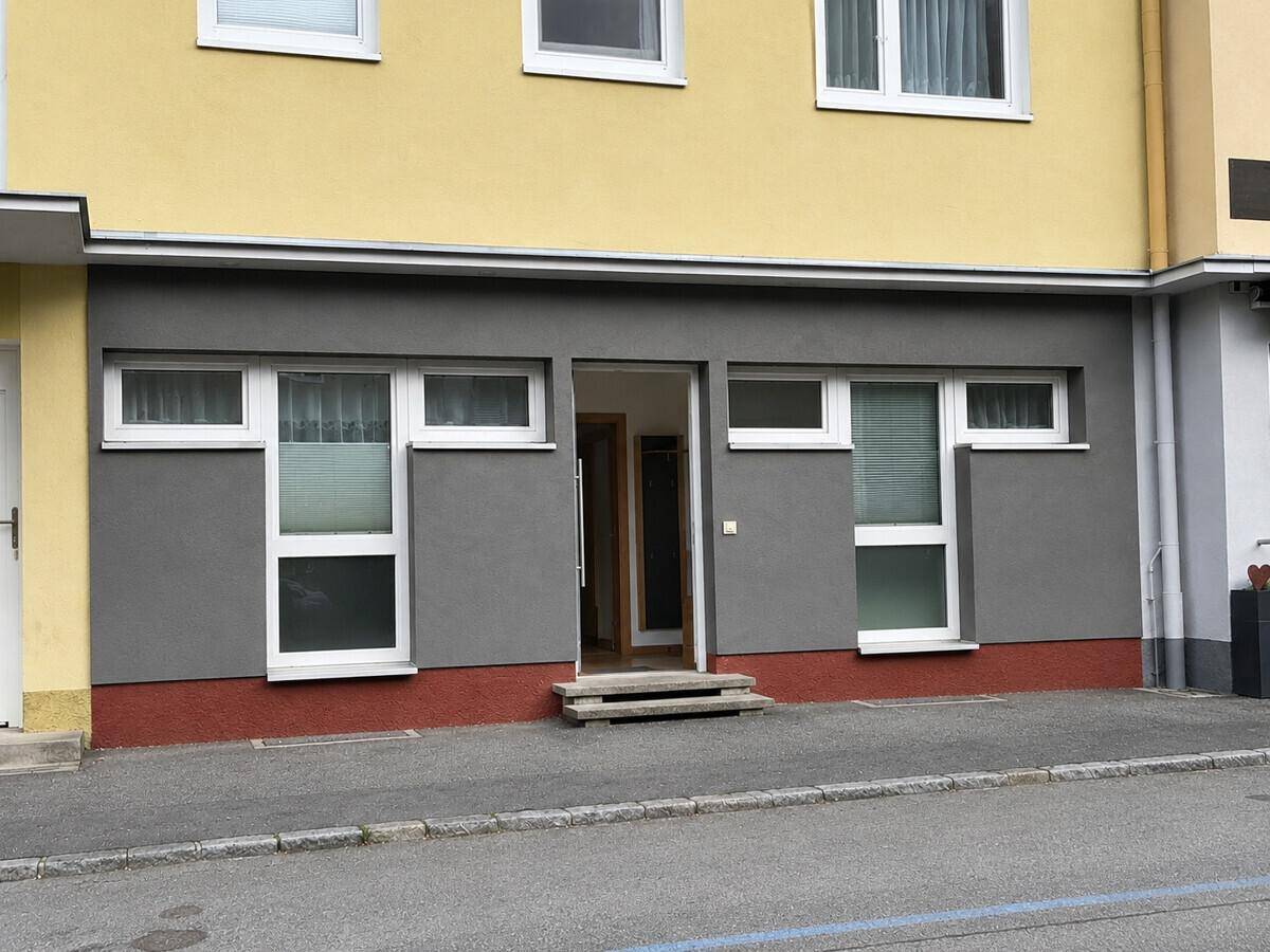 Fassade eines Gebäudes mit mehreren Fenstern und Eingangsbereich auf Straßenniveau.