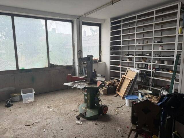 Geräumiger Werkstattraum mit Regalen, großen Fenstern und Arbeitsgeräten.