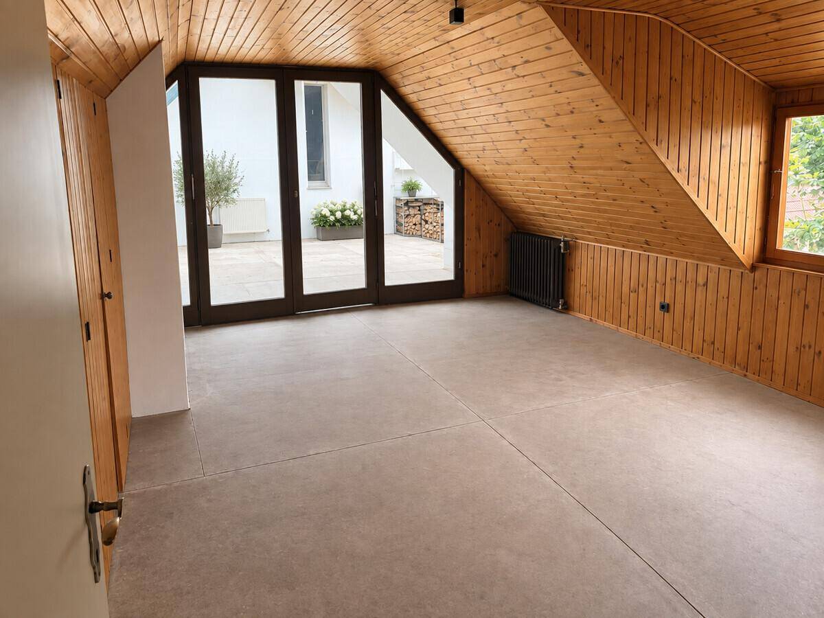 Heller Raum mit Fliesenboden, Holzverkleidung und Zugang zu einer Außenterrasse.