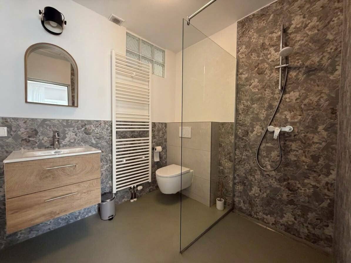Modernes Badezimmer mit begehbarer Dusche, Holzwaschtisch und beheiztem Handtuchhalter.