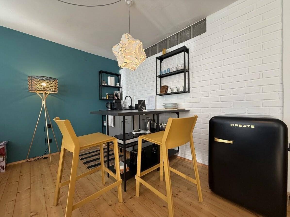 Kompakte Küchenzeile mit Bartheke, Hockern und offenem Regal in modernem Design.