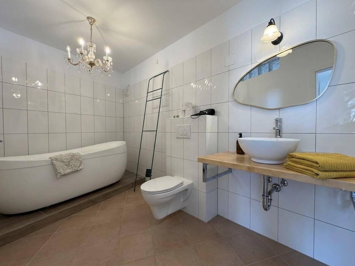 Modernes Badezimmer mit freistehender Badewanne, Wand-WC und Aufsatzwaschbecken.