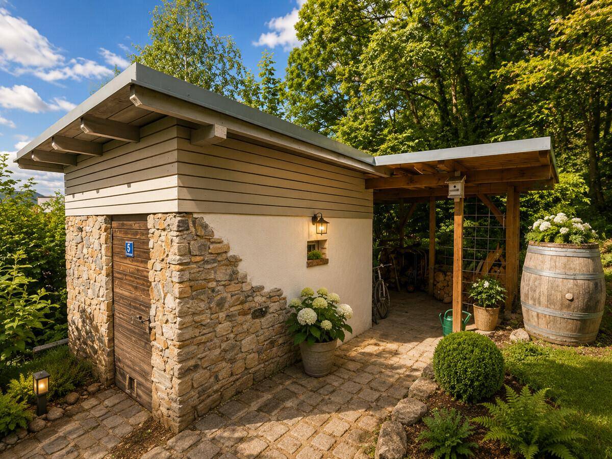 Rustikales Gartenhaus mit Steinverkleidung, Holztür und überdachtem Unterstand.