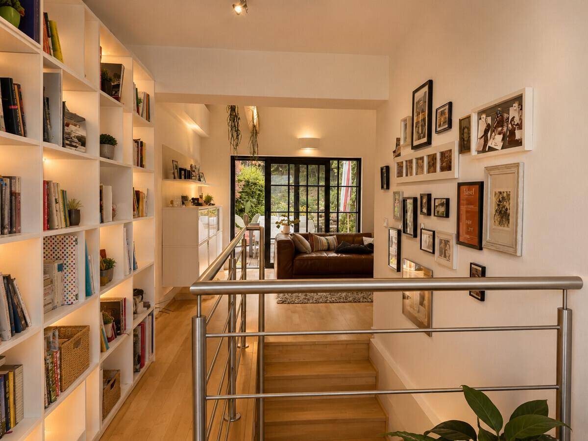 Heller Flur mit Holztreppe, integrierten Bücherregalen und Blick in den Wohnbereich.