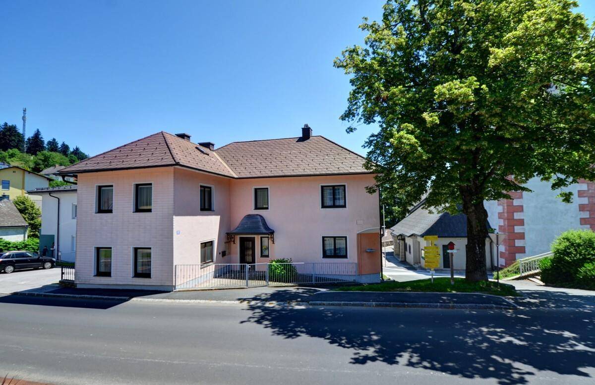 Ansicht des rosa verputzten Hauses mit Satteldach und gepflegtem Vorgarten von der Straße aus.