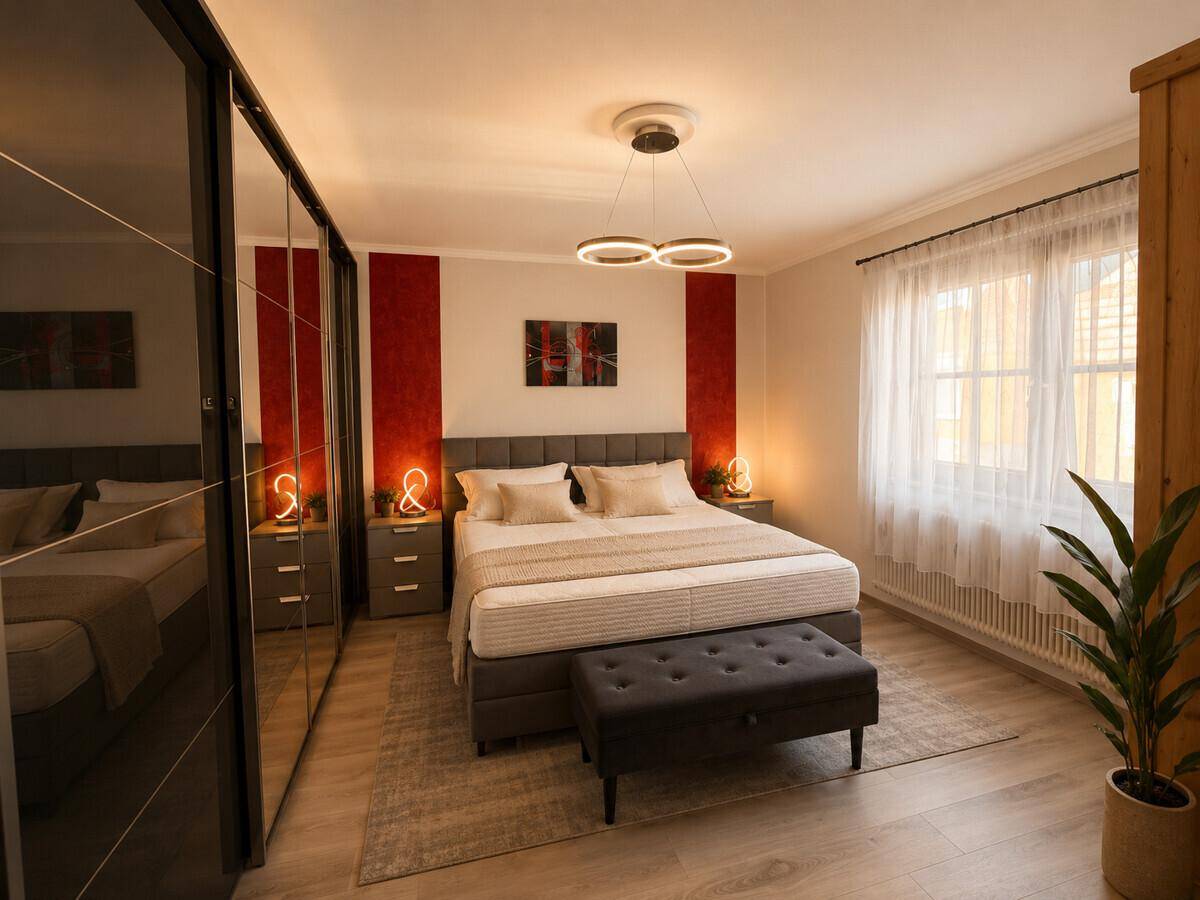 Modernes Schlafzimmer mit großem Bett, Spiegelschränken und indirekter Beleuchtung.