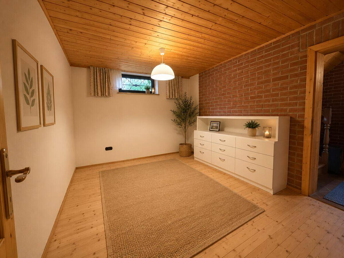 Gemütliches Zimmer mit Holzbalkendecke, Ziegelwand und großem Fenster.