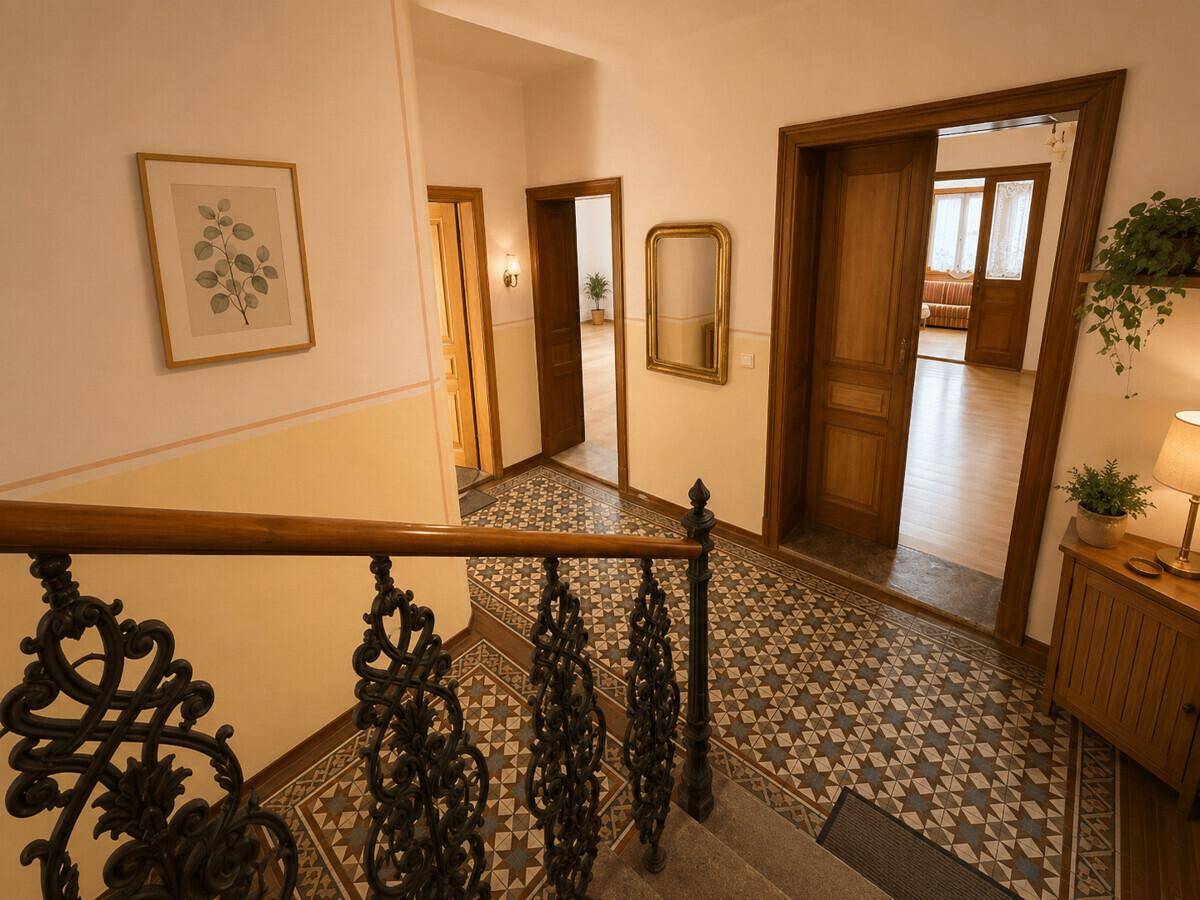 Geräumiger Flur mit gemusterten Fliesen, Holztreppe und dekorativem Geländer.