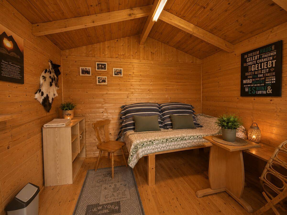 Gemütliches Schlafzimmer im Hüttenstil mit Holzverkleidung und Einzelbett.