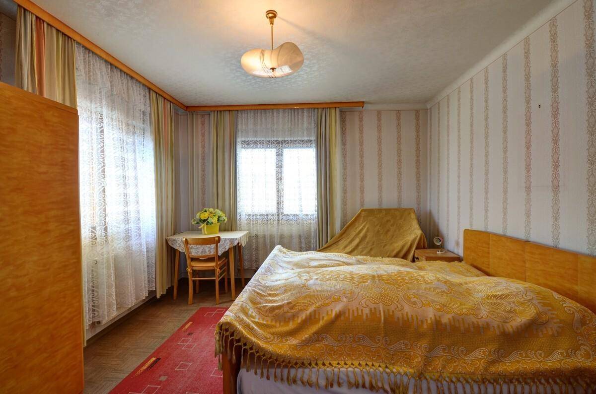 Schlafzimmer mit Doppelbett, Nachttischen und gemusterten Tapeten im traditionellen Stil.