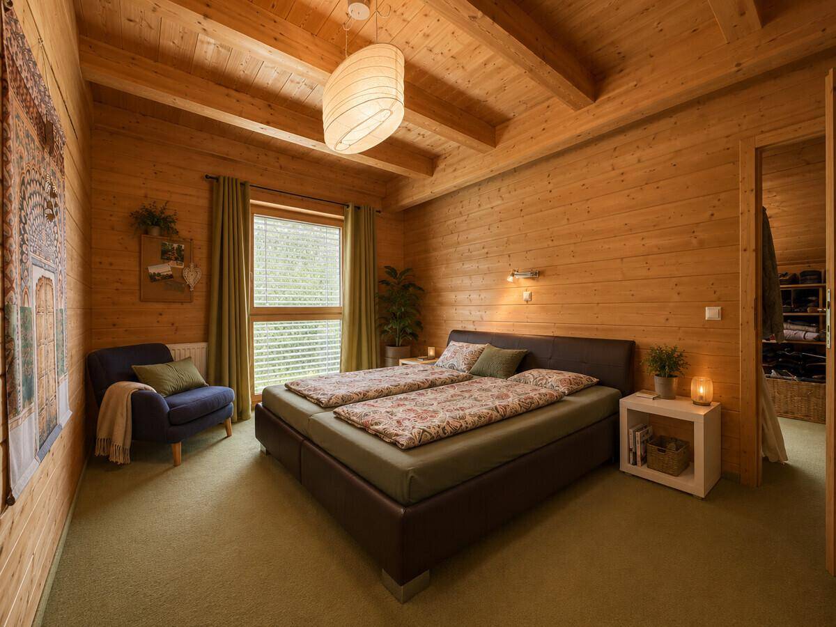 Gemütliches Schlafzimmer mit Doppelbett, Holzwänden und Zugang zum begehbaren Kleiderschrank.