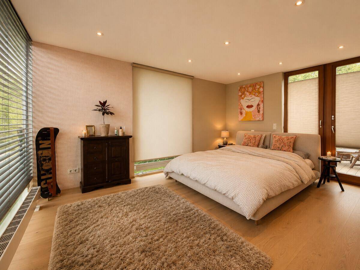 Geräumiges Schlafzimmer mit Holzboden, großen Fenstern und Zugang zur Terrasse.