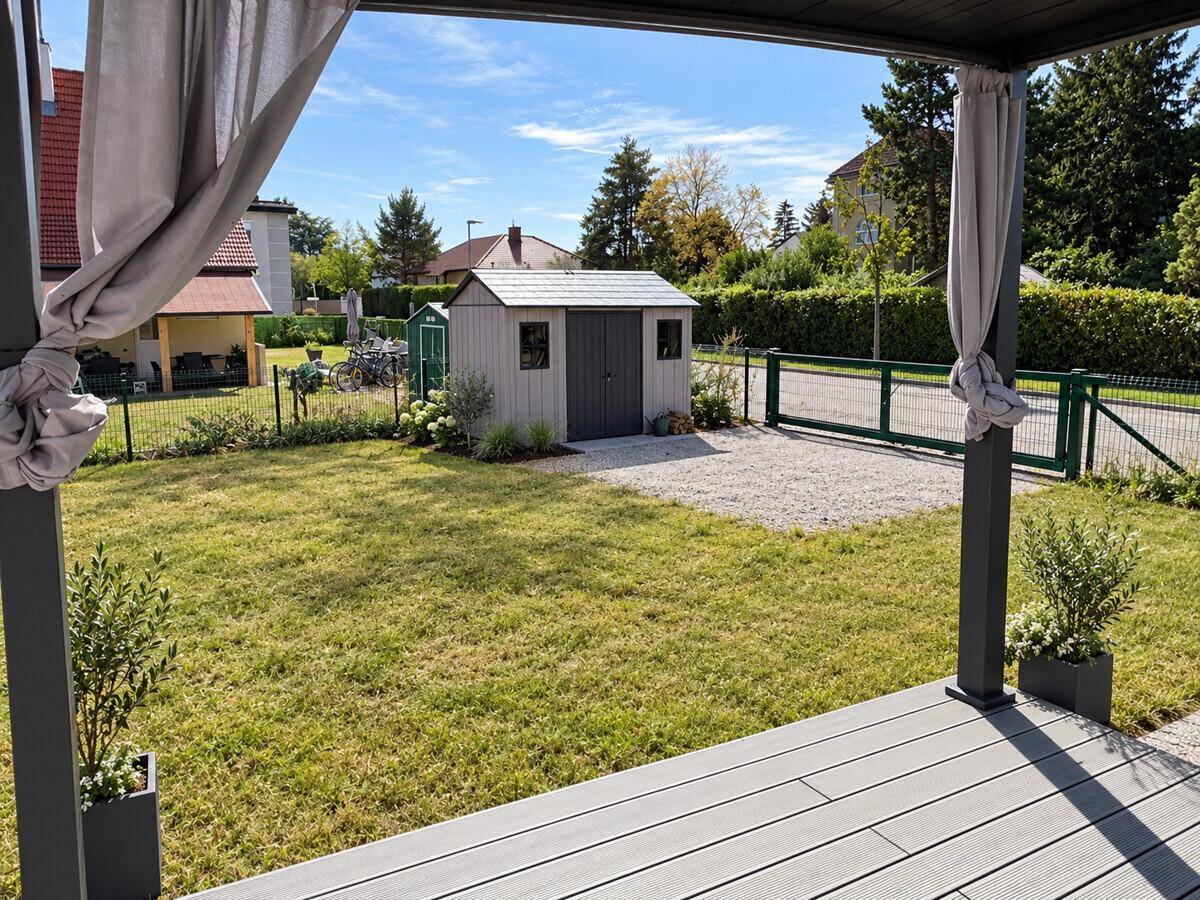 Gepflegter Garten mit Rasenfläche, Gartenhaus und Blick auf die Umgebung.