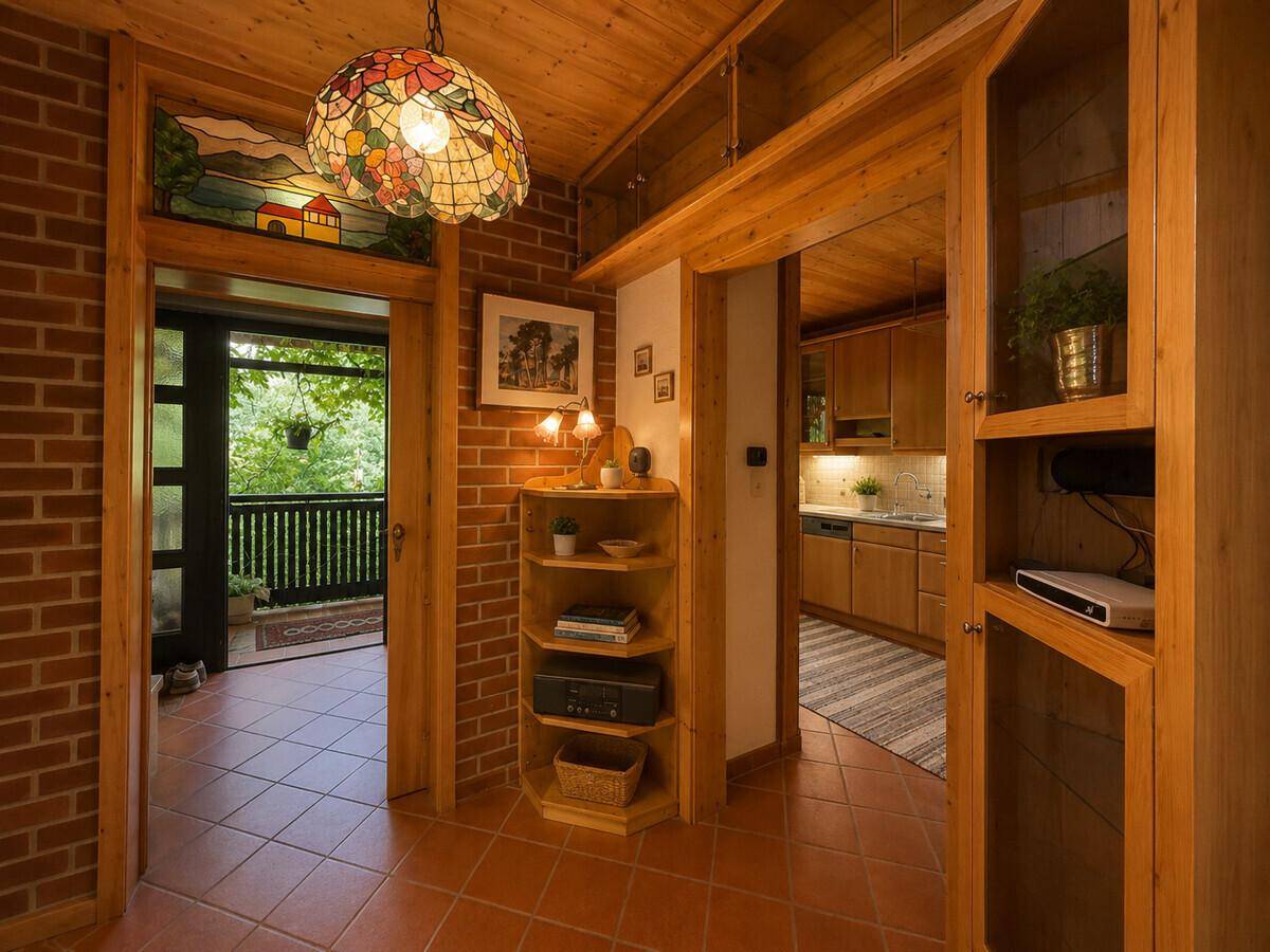 Heller Eingangsbereich mit Terrakotta-Boden, Ziegelwand und Zugang zu Küche und Balkon.