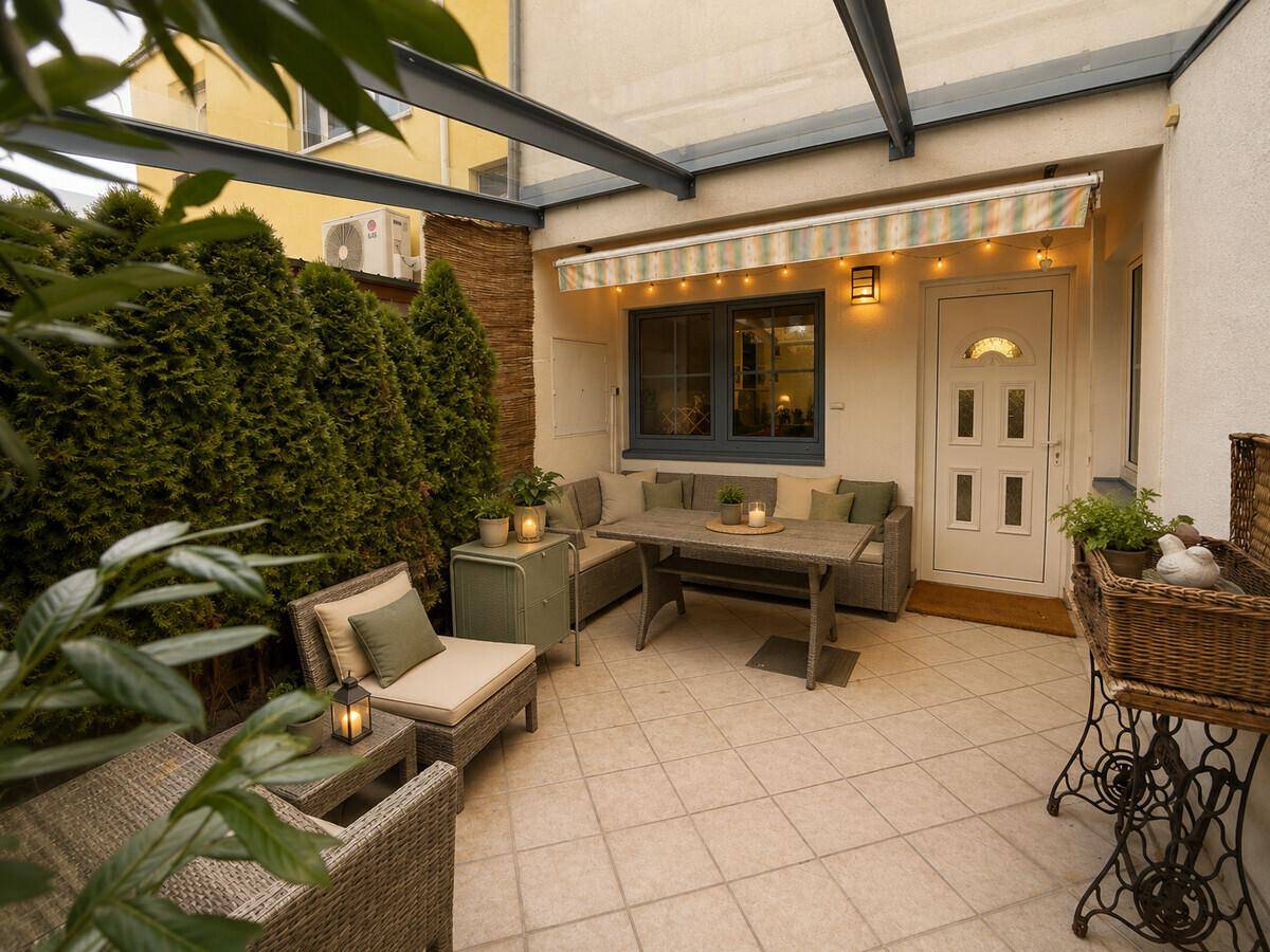 Gemütliche Terrasse mit Sitzgelegenheiten, Markise und gepflegten Pflanzen im Außenbereich.