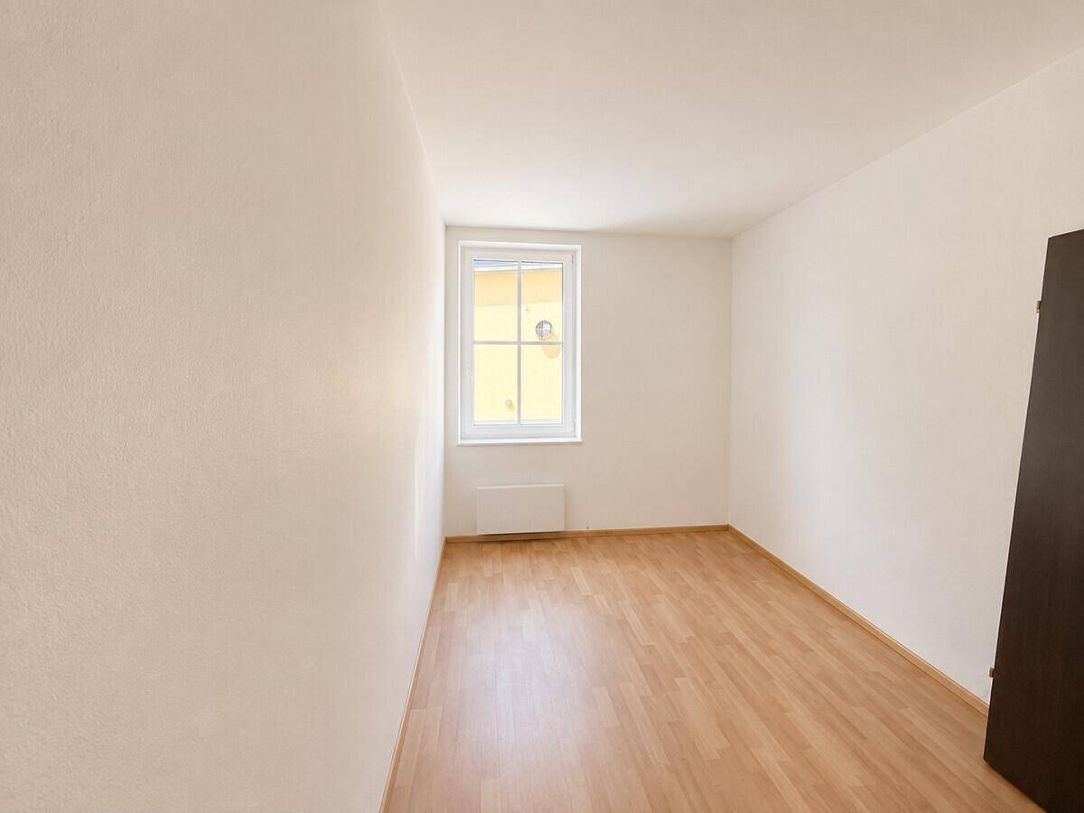 Kleines, helles Zimmer mit Laminatboden und einem Fenster, das viel Licht spendet.
