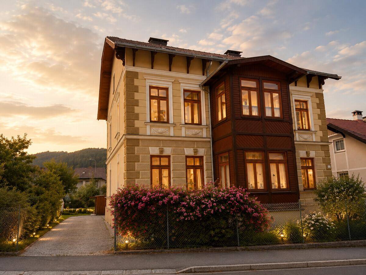 Historisches Gebäude mit Erker, gepflegtem Vorgarten und Zufahrt bei Sonnenuntergang.