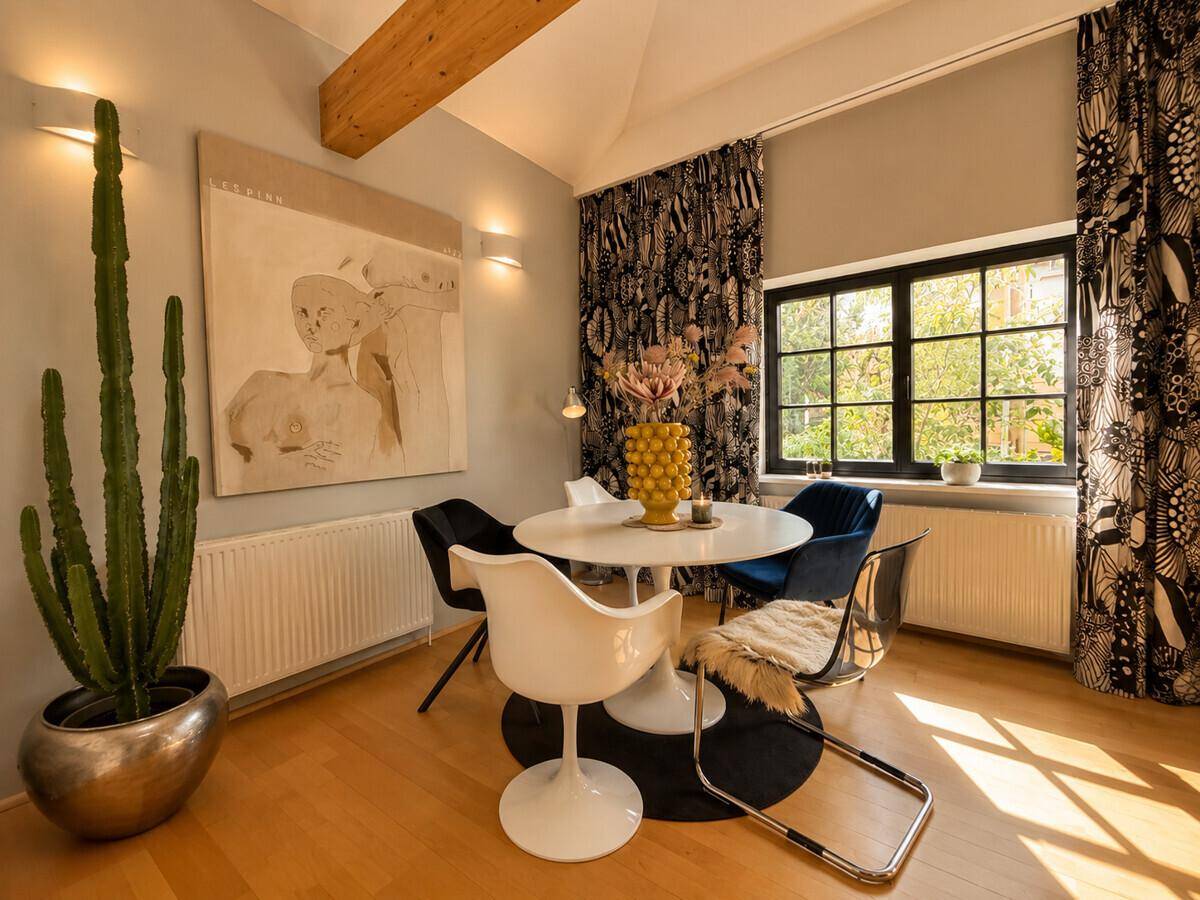 Heller Essbereich mit modernem runden Tisch, Designerstühlen und dekorativen Vorhängen.